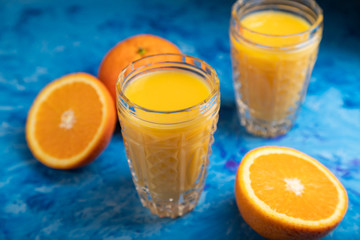 Glass of orange juice on a black and blue background. Side view, close up.