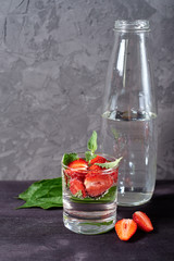 Infused water with strawberry and mint in sparkling glasses on wood black table background, copy space. Cold summer drink. Mineral water