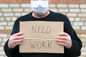 concept unemployment and coronavirus a man in a medical hygienic mask is holding a cardboard tablet...