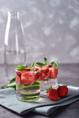 Infused water with strawberry and mint in sparkling glass on table, copy space. Cold summer drink. Mineral water
