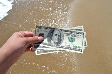 Girl holding a money bill of 300 dollars on background of sea waves