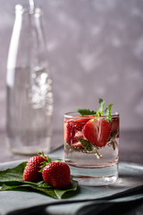 Infused water with strawberry and mint in sparkling glass on table, copy space. Cold summer drink. Mineral water