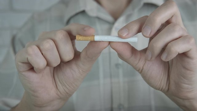 Break a cigarette. Male hands break a cigarette.