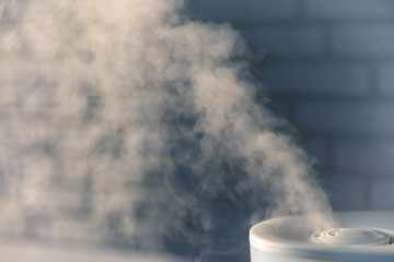 Humidifier spreading steam with white brick wall background - obrazy, fototapety, plakaty