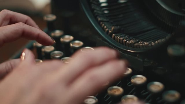 Closeup slow motion shot of woman typing on old typewriter. Stationary Cinematic Isolated typewriter shot.