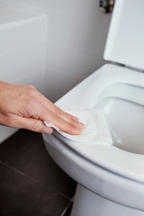 man cleaning the toilet seat with a piece of paper