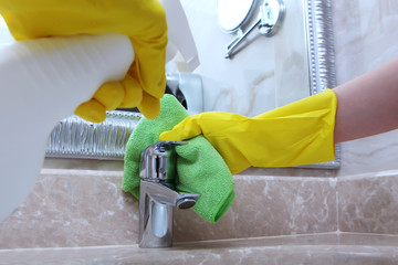 Cleaning service at the hotel or at home. Cleaning the faucet in the bathroom.