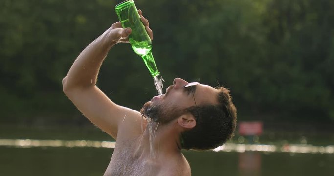 Man pouring drink into open mouth from bottle
