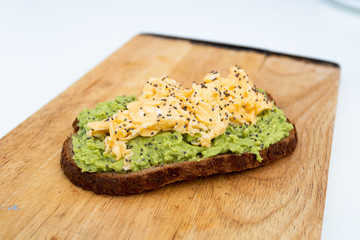 whole wheat toast with guacamole and omelette on top of a wood