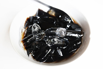 Thai Sweet dessert grass jelly with Ice in white bowl. A kind of Chinese vegetable is black jelly or Herbs can relieve heat in human body system and Aphthous stomatitis in summertime.