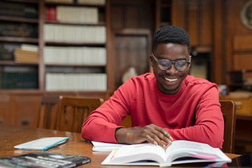 Happy university student reading in library