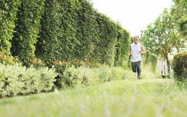 Happy Healthy Asian Senior man enjoying workout at outdoor with copy space. Portrait of Smiling Elderly male jogging exercise at the park. Health, Lifestyle, Wellness.  