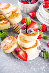 Cottage cheese pancakes with honey and various summer berry on grey background, summer breakfast or lunch