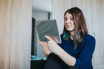 Fototapeta premium Woman bonding with friends during quarantine indoors. Female using tablet.