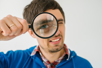 on a gray background young man with a magnifying glass