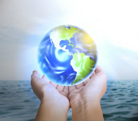 Woman holding Earth near ocean, closeup view