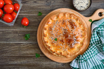 Cabbage pie. Tasty freshly baked homemade vegetable pie with cabbage, spinach, eggs and sesame seeds on a wooden board. Top view.