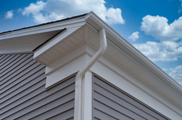 White frame gutter guard system, with gray horizontal vinyl siding fascia, drip edge, soffit, on a...