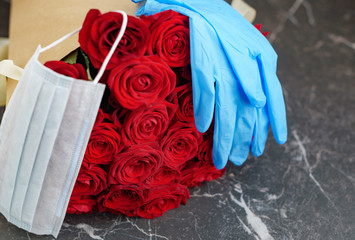 contactless delivery - face mask medical glove and bouquet of red roses, the concept of quarantine and isolation during the coronavirus pandemic and the decline economy of flower businesses and shops