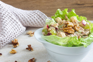 Homemade waldorf salad made of celery, apples and walnuts, served on a bed of fresh leaf lettuce.