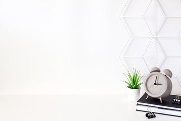 School supplies and clock on the background of an empty white wall.