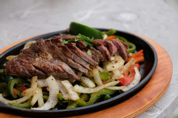 close up chopped steak with onion and pepper in plate on table. blur background