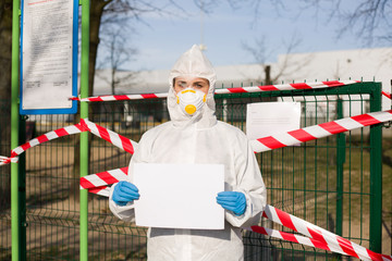 Osoba  z białą kartką w dłoniach stojąca przed taśmami zabezpieczającymi wejście do parku w czasie pandemii - obrazy, fototapety, plakaty