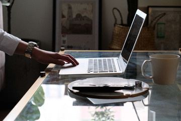 side view of business man's hand using laptop computer on table. Working from home concept 