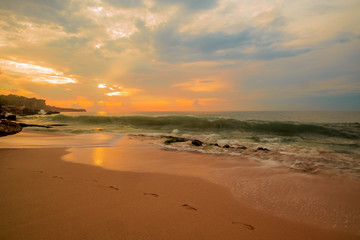 Seascape. Sunset time at the beach. Beach background with footprints in the sand. Tegal Wangi beach, Bali, Indonesia