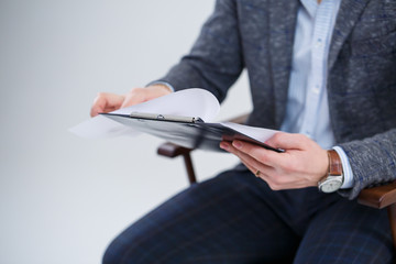 Business man businessman in a suit sitting on a wooden chair and throws documents. On a white...