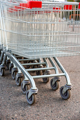 Many empty shopping carts in a row, standing on the outdoor near a supermarket