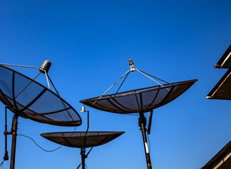 Parabolic satellite antenna on blue sky background closeup