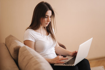 Young woman work at home in quarantine. Woman use laptop on sofa. Woman study distance learning