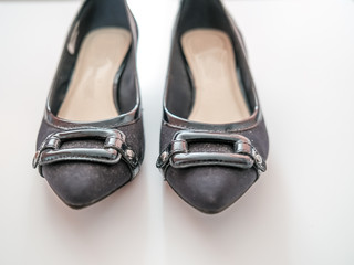 Front on view of a pair of ladies black heeled shoes with a metal square at the front on a plain white background