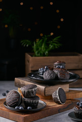 chocolate vegan muffins on a wooden background. Blueberry  on side. Dark and moody photo style.