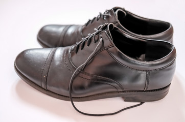 Fototapeta na wymiar Close up of well worn classic black leather men's shoes on a plain white background with selective focus