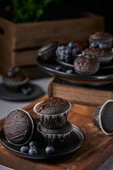 chocolate vegan muffins on a wooden background. Blueberry  on side. Dark and moody photo style.