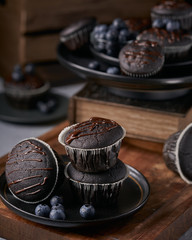 chocolate vegan muffins on a wooden background. Blueberry  on side. Dark and moody photo style.