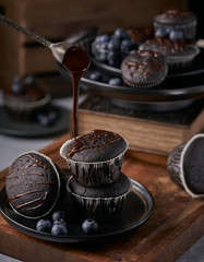 chocolate vegan muffins on a wooden background. Blueberry  on side. Dark and moody photo style.