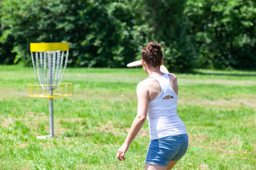 Young woman playing flying disc sport game in the park