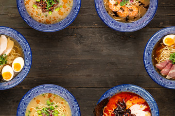 Set of different types of Japanese ramen, tantanmen, shio ramen, shrimp, wood mushrooms, top view on a wooden background, in blue traditional bowls