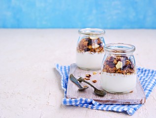 Homemade baked oat granola with nuts, dried cranberries and honey and unsweetened natural yogurt in...