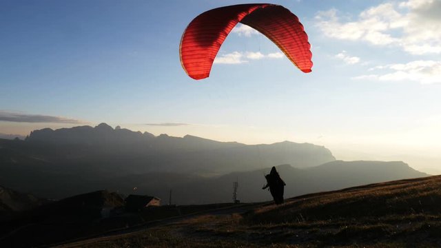 Paraglider run and accelerates himself to take off from the mountain of Seceda.