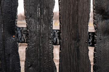 Burnt fence boards after a fire in a private house.
