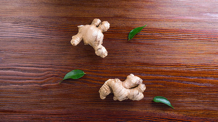 Ginger root with leaves on wooden background