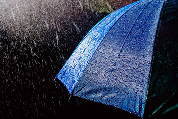 Multicolored umbrella under raindrops isolated on black as background.