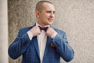 Bridegroom in a wedding suit straightens the butterfly. Beautiful wedding. Portrait of the groom.