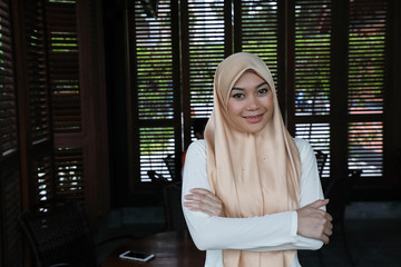 Young asian malay man woman with headscarf stand confident look at camera rustic cafe table