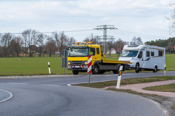 Ein Abschleppwagen mit einem Wohnmobil fährt in den Kreisverkehr ein 