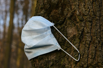 Girl puts a mask on the tree trunk, protecting nature from the virus